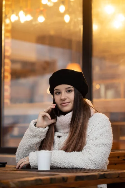 一个年轻的女人在餐馆用电话交谈 女孩喝咖啡 — 图库照片