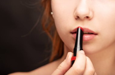 Makyöz kırmızı ruj kullanıyor. Telafi sürecinde. Genç ve güzel bir modelin stüdyo çekimi..