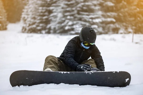 Молодая девушка сноубордистка привязывает свой сноуборд — стоковое фото