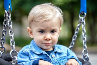 Çocuk parkında sallanan küçük sarı saçlı çocuk. Mutlu çocuk..