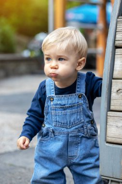Küçük sarı saçlı bebek aptalca suratlar yapıyor. Sevimli çocuk..