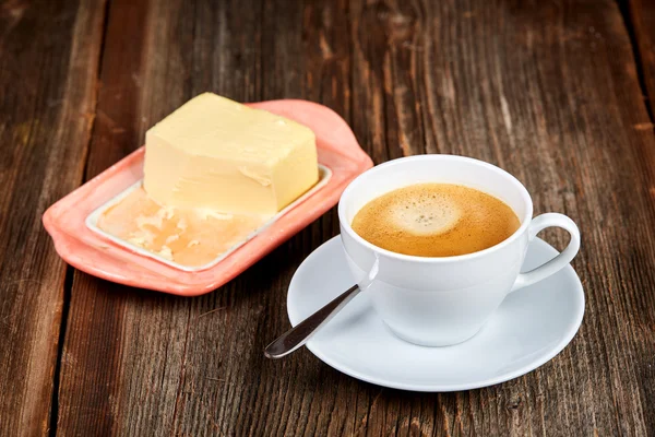 Coffe e manteiga em um prato em uma mesa de madeira — Fotografia de Stock