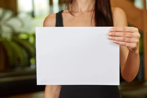 Young caucasian woman holding white sheet of paper — Stock Photo, Image