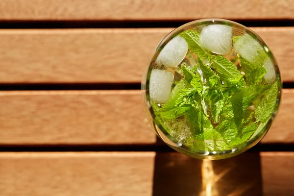 Свежий мятный напиток со льдом в стакане на деревянном столе — стоковое фото