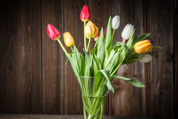 Barevné tulipány ve váze na dřevěný stůl — Stock fotografie