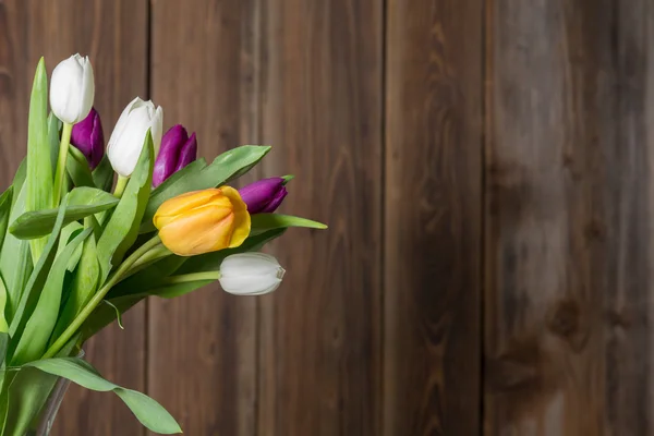 Barevné tulipány ve váze na dřevěný stůl — Stock fotografie