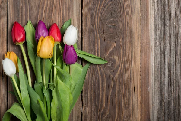 Barevné tulipány na dřevěné pozadí — Stock fotografie