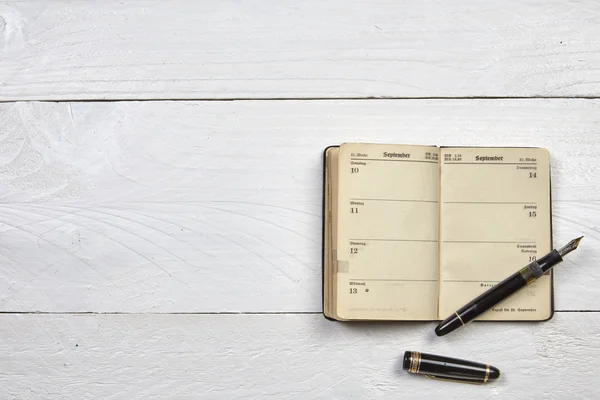 Antique fountain pen and old calendar on a white wooden table — Stock Photo, Image