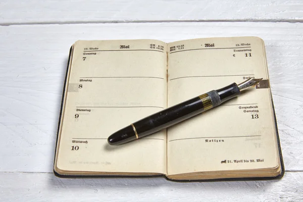 Antique fountain pen and old calendar on a white wooden table — Stock Photo, Image