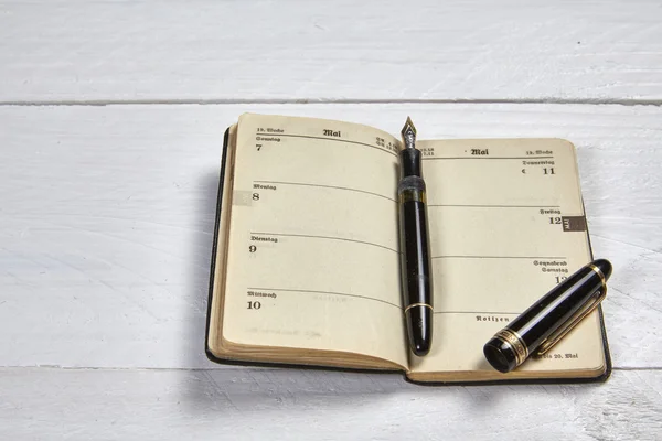 Bolígrafo antiguo y calendario antiguo en una mesa de madera blanca —  Fotos de Stock