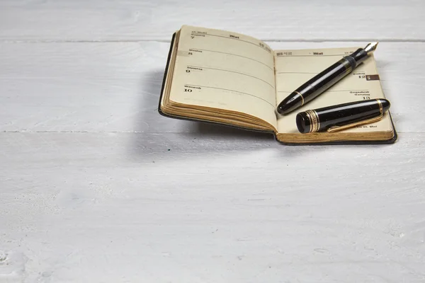 Bolígrafo antiguo y calendario antiguo en una mesa de madera blanca —  Fotos de Stock