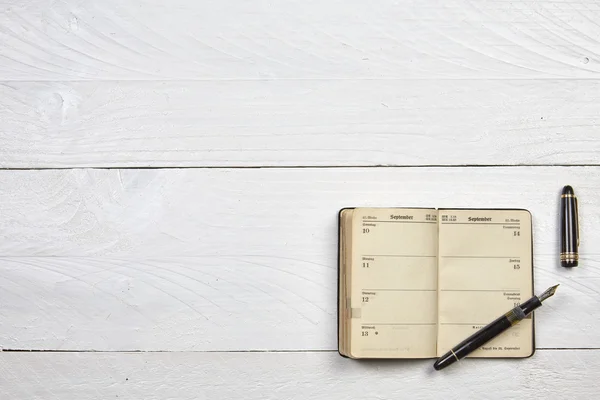 Antique fountain pen and old calendar on a white wooden table — Stock Photo, Image