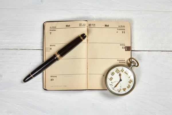 Antique fountain pen, old calendar and watch on a white wooden t — Stock Photo, Image