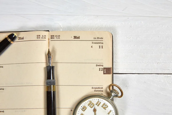 Antique fountain pen, old calendar and watch on a white wooden t — Stock Photo, Image