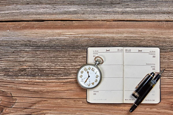 Caneta-tinteiro antiga, calendário antigo e relógio em uma mesa de madeira — Fotografia de Stock