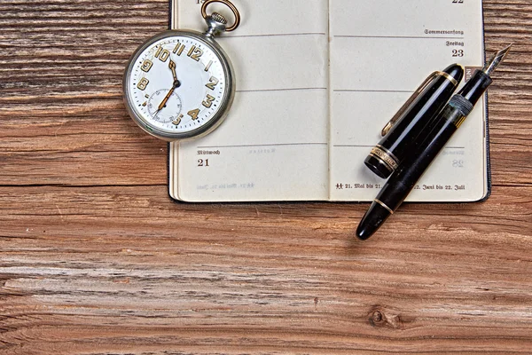 Caneta-tinteiro antiga, calendário antigo e relógio em uma mesa de madeira — Fotografia de Stock