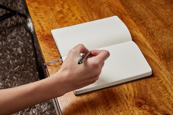 Mulher escrevendo em um livro com caneta — Fotografia de Stock