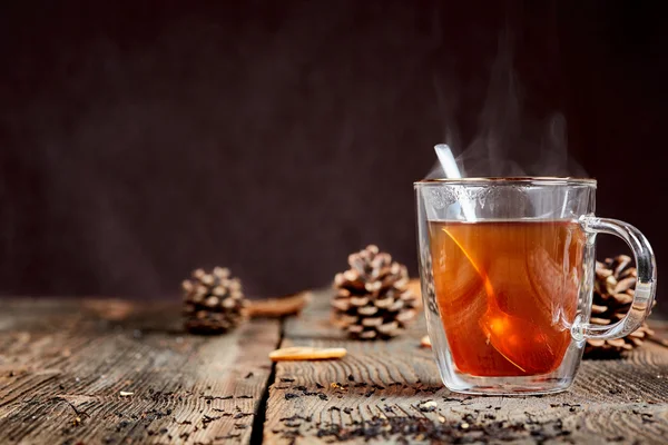 Tè fumante e miele su un tavolo di legno con pigne — Foto Stock