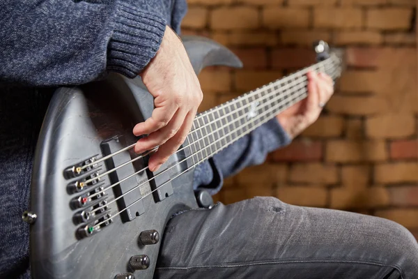 Le bassiste joue de la basse devant un mur de briques — Photo