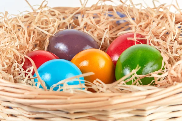 Pasen mand met gekleurde eieren en stro — Stockfoto