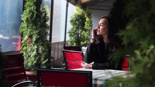 Menina muito bonita conversando no telefone sentado em um restaurante . — Vídeo de Stock