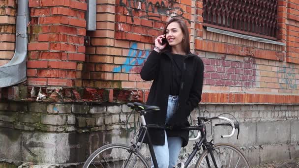 Mooi meisje met een fiets, praten over de telefoon. het meisje is zeer aantrekkelijk. — Stockvideo