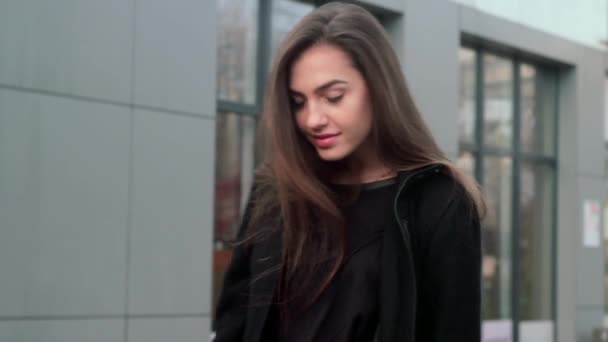 Nagyon szép és aranyos lány pózol a kamera a városban. Ő kiegyenesíti a haját, és a gyönyörű mosoly. — Stock videók