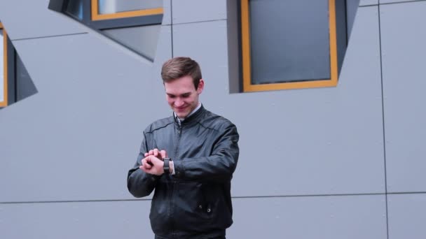 Zeer aardige Man met behulp van slimme horloges. Hij drukt op een vinger op het scherm, staande in de buurt van the Office Building. — Stockvideo