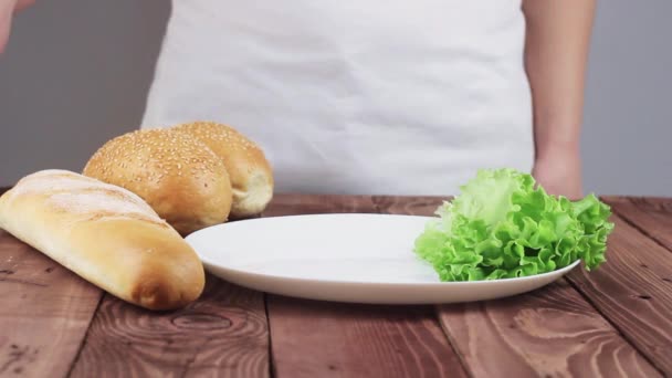 Chef zet eten op het bord. op het bord staan kaas, ham, tomaten, komkommers en sla. In de buurt ligt een stokbrood en een broodje. — Stockvideo