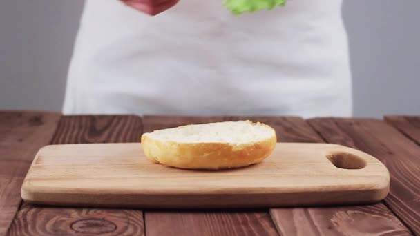 O cozinheiro prepara um hambúrguer. Hambúrguer Consiste em Buns, Queijo, Carne, Tomate e Alface. Movimento lento . — Vídeo de Stock