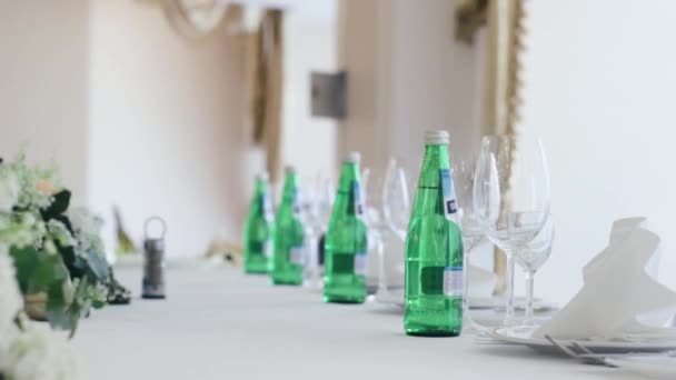 Un salón de banquetes para bodas. sobre la mesa Colocar flores y botellas de agua mineral. Todo decorado . — Vídeos de Stock