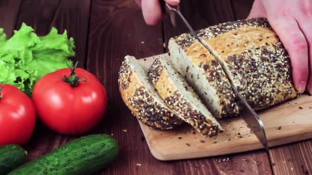 Na tabuli vaří Bakes Bread. Chléb se sezamovou semínka. na stole ležely rajčata, hlávkový salát a okurky. Restaurační kuchyně. — Stock video