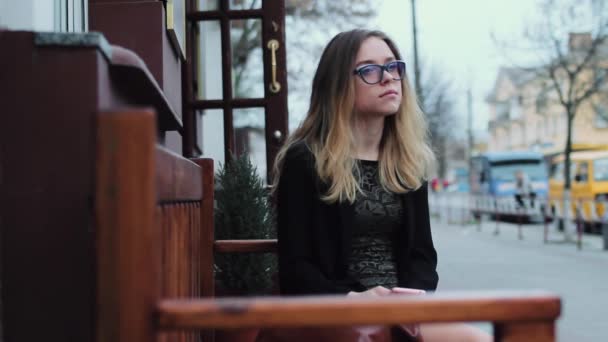 Belle femme en attente homme assis sur un banc dans la ville. la fille est très triste. Bonsoir. . — Video