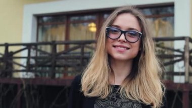 Çok güzel ve güzel Kız bardaklarda kameraya bakıyor ve gülümsüyor. Kadın elini dalgalar. Kız çok çekici gülümseme.