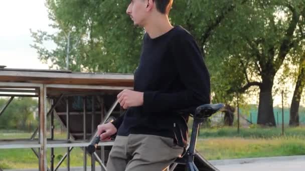 Hombre guapo parado cerca de una bicicleta al atardecer. en Spring Street . — Vídeos de Stock