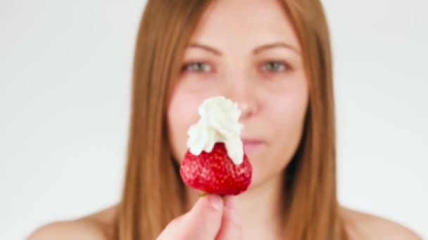Mooi meisje houdt een aardbeien en room. Close-Up. een vrouw op een witte achtergrond. — Stockvideo