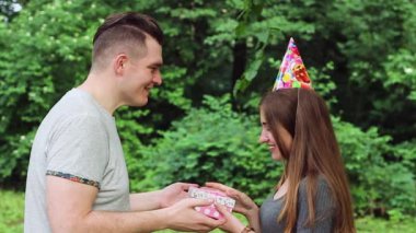 Adam kıza doğum gününde bir hediye veriyor. Ağır çekim. Mutlu bir kadın. O sevinç için atlama ve bir adam sarılma hediye açar.