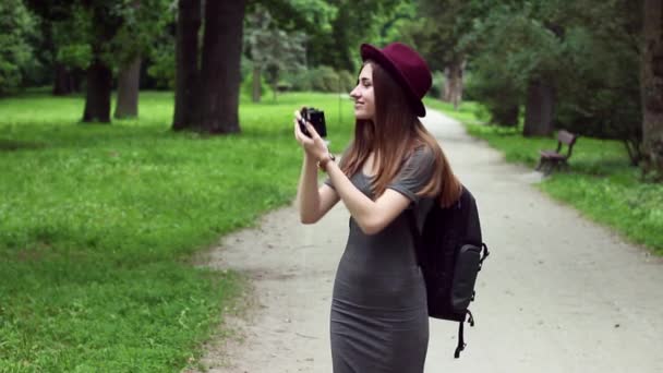 Woman Tourist Walking in the Park and Photographed Sights (en inglés). La mujer es muy hermosa. Ella está usando un sombrero rojo y un vestido gris . — Vídeo de stock