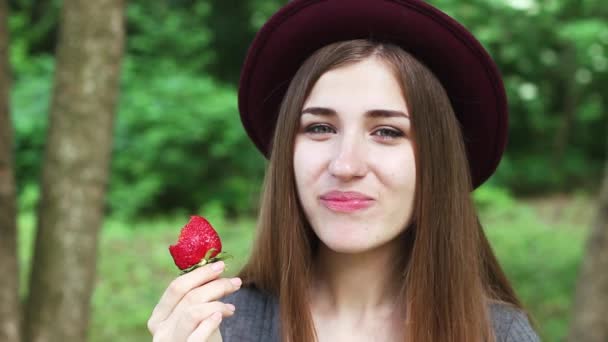 Gyönyörű lány eszik szamóca, a parkban. — Stock videók