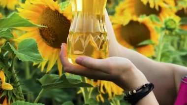 Ayçiçeği ile sahada ayçiçek yağı bir şişe tutan bir kız.