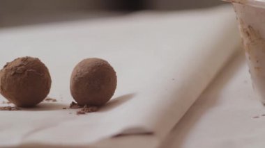 Kadın koyar pudra bir parşömen kağıt üzerine çikolata topları. Şeker fabrikası.