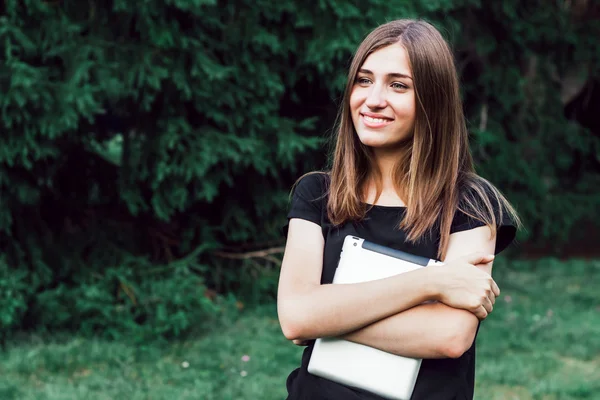 Bir tablet tutan bir parkta duran güzel kız öğrenci.