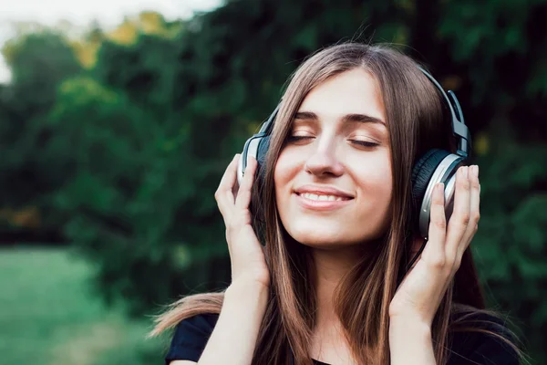 Vacker ung flicka lyssna på musik i hörlurar. Stockbild