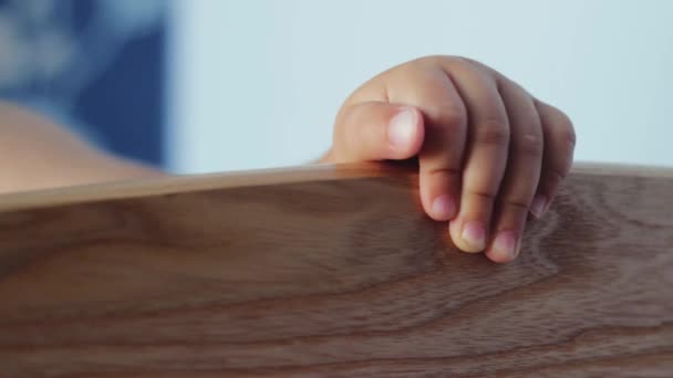 Ευτυχισμένο μωρό παίζοντας σε μια κούνια. Το χέρι ενός παιδιού . — Αρχείο Βίντεο