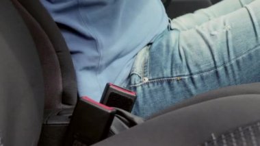 Sürücü arabada oturan emniyet kemerini tak. Mavi şort ve tişört giymiş bir adam.