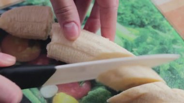 Kız muz bıçağını keser. Meyve salatası hazırlayan aşçı.