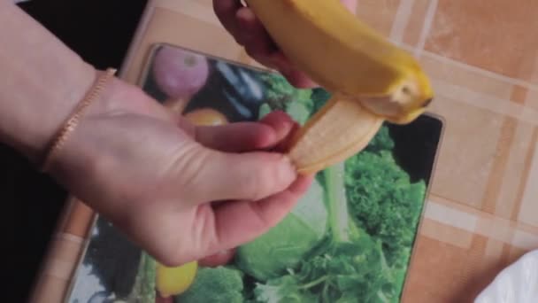 Het meisje reinigt een banaan. — Stockvideo