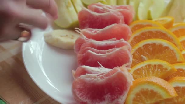 Mujer Prepara un plato de fruta. Plátanos, naranjas, pomelos, manzanas . — Vídeos de Stock