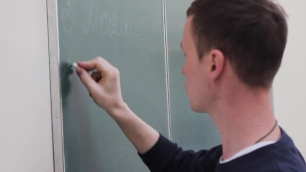 Studenten skriver på svarta tavlan vid universitetet. — Stockvideo