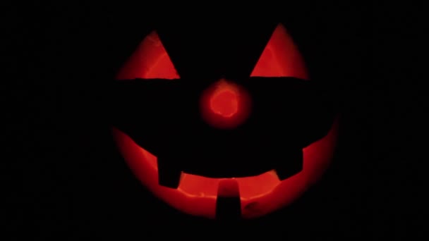 Halloween. Holiday Glowing Pumpkin is in The dark. Nearby are two candles. Angry face. — Stock Video